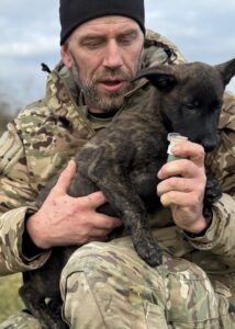 Militærinstruktør Thomas vugger en belgisk malinois-hvalp.
