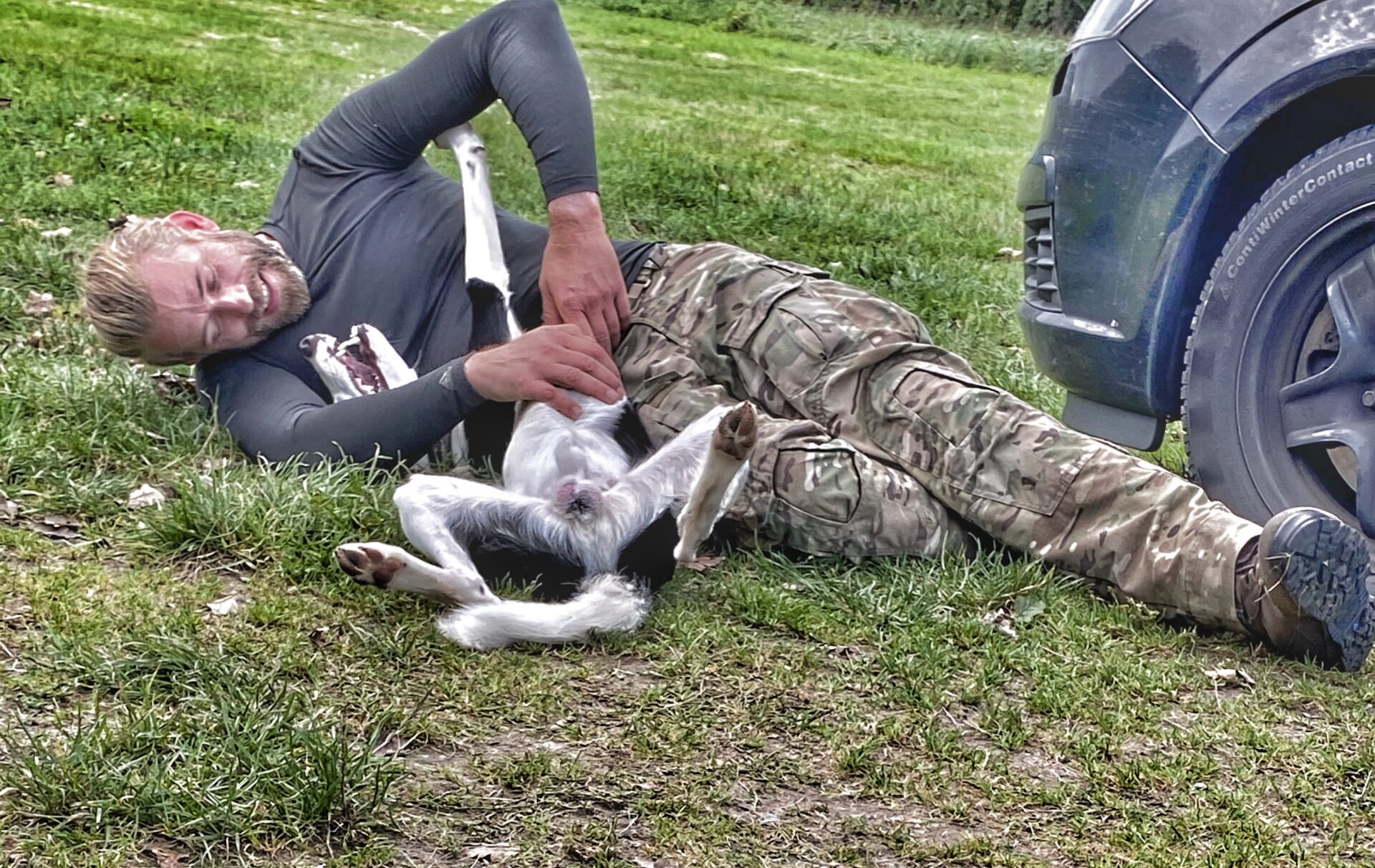 Mand brydes legende med sin border collie hund på græsset.